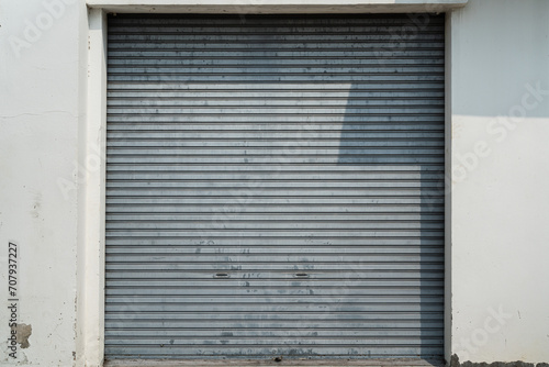 Closed metal grate rolling door of the warehouse storage or service garage. View from in front of the building  industrial building place.