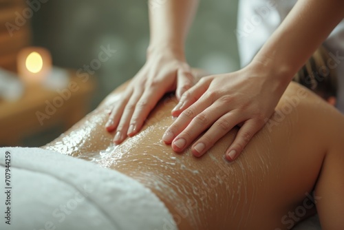 A woman is receiving a relaxing back massage at a spa. This image can be used to promote the benefits of spa treatments and self-care