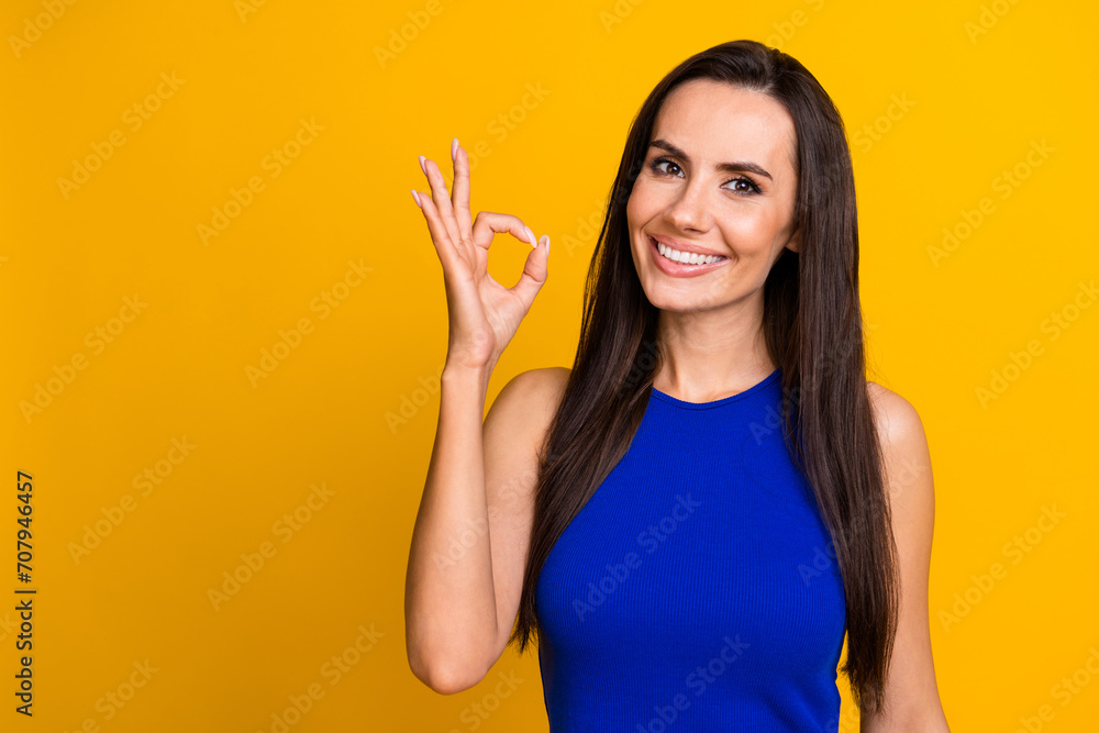 Photo of positive pretty lady dressed blue top showing okey empty space isolated yellow color background Photo of positive pretty lady dressed blue top showing okey empty space isolated yellow color background