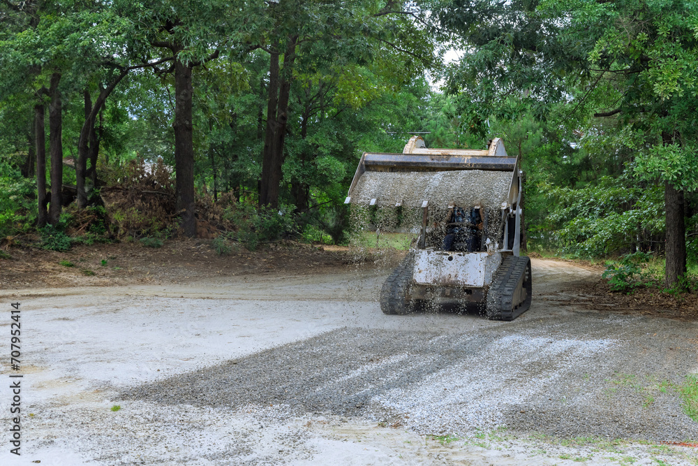 Bobcat mini loader is moving bucket of crushed stone gravel during construction operations