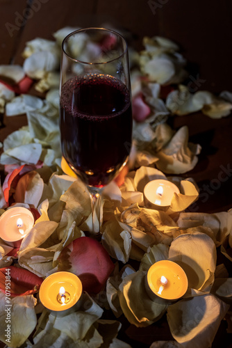 Wine glass with rose petals and candles 