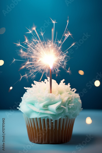 Festive cupcake with glitter and splashes on a blue background. Birthday cupcake with candle on blurred background.