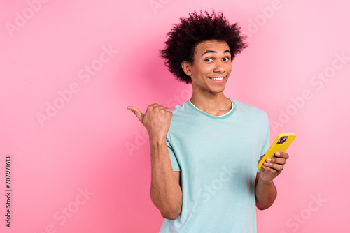 Photo of excited cool man dressed blue t-shirt texting modern gadget thumb empty space isolated pink color background