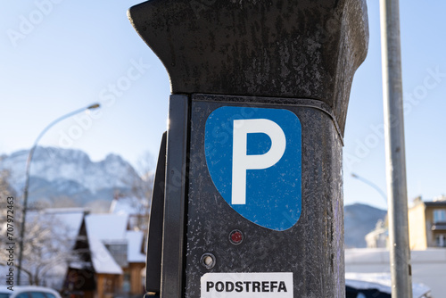 Parking meter, Parkometr or Parkomat in paid parking zone of Zakopane city, Poland. Town car park pay and display ticket machine. Tatra Mountains Giewont in background. Podstrefa means subzone. photo