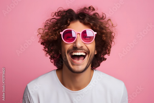 Young man with curly hair wearing pink sunglasses on pink background © jimenezar