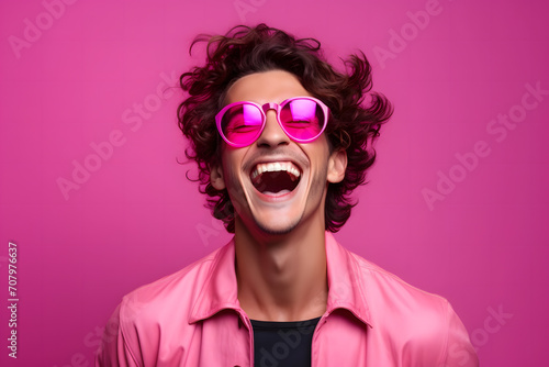 Happy young man wearing pink sunglasses on a pink background