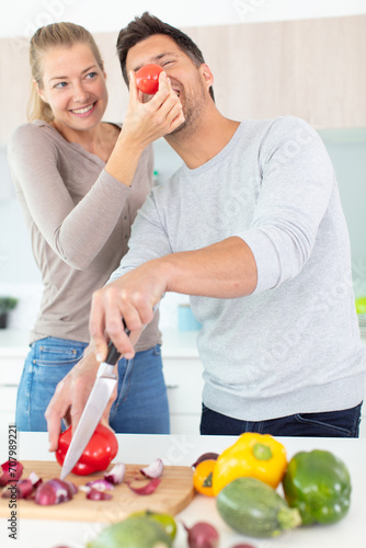 playful couple cooking together in the kitchen photo