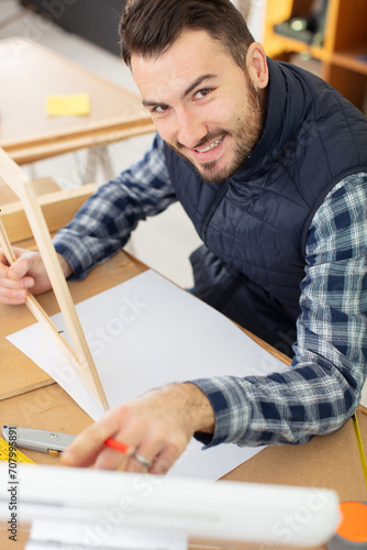 designer sat at desk holding wooden frame