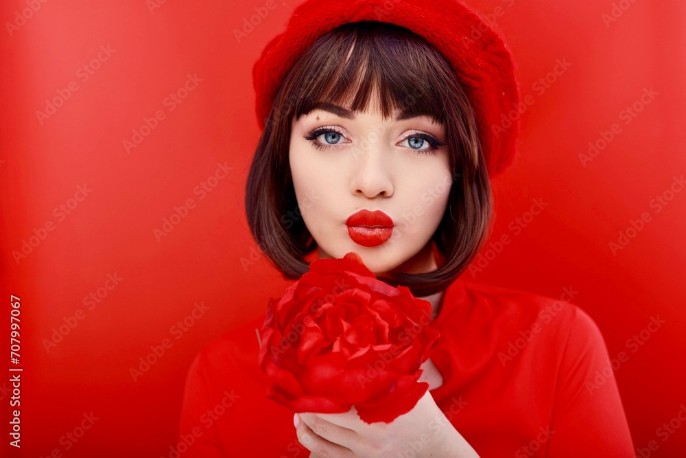 cute girl in a red head holds a large red flower in her hands and smiles cute girl in a red head holds a large red flower in her hands and smiles
