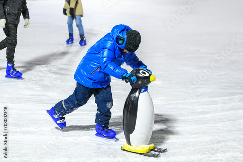 Quadro em tela Cherepovets, Russia, January 7, 2024, Boy in warm clothes  learning ice skating with helper on ice rink