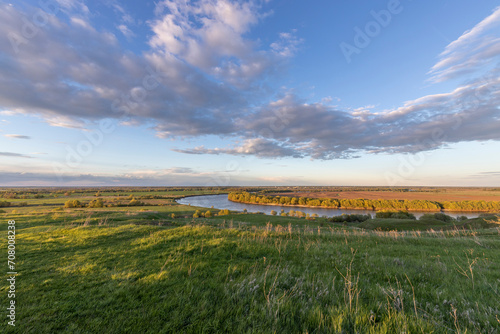 View of water meadows and fields in the countryside on a May evening  the setting rays of the sun illuminate the green grass.