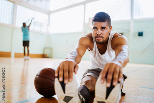 Young man stretching before playing basketball in an indoor basketball gym photo