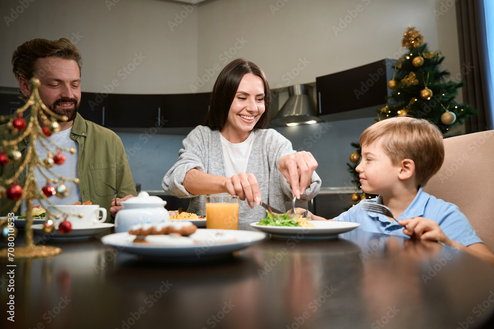 Cheerful mother enjoying breakfast with her family during winter holidays