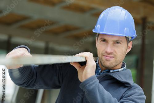 contractor in hard hat holding plank of wood