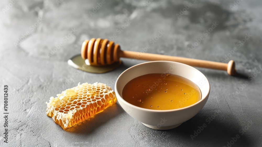 minimalist setting with a bowl of honey, a honey comb and a wooden dipper on a gray background minimalist setting with a bowl of honey, a honey comb and a wooden dipper on a gray background