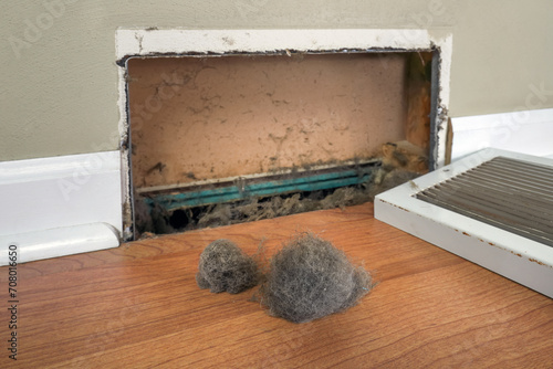Dirty register wall vent with dust clogging the duct opening in a home