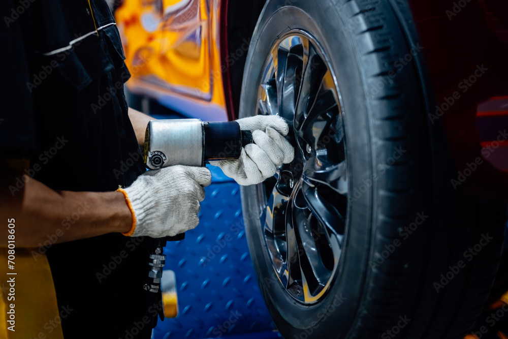 Mechanic with screwdriver repairing car wheel in workshop. Changes tire spare parts. Mechanic with screwdriver repairing car wheel in workshop. Changes tire spare parts.