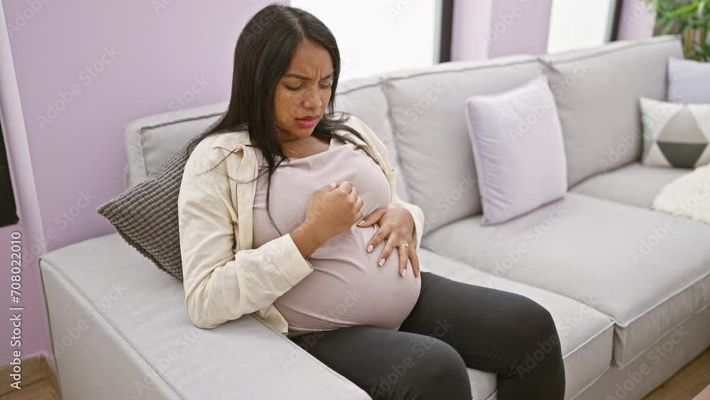 Young pregnant woman touching belly sitting on sofa coughing at home Young pregnant woman touching belly sitting on sofa coughing at home
