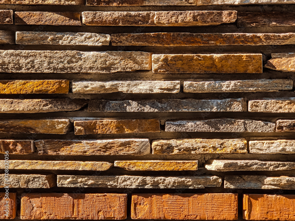 The masonry wall are made of gray wild flat stone and bricks. Side natural sunlight. Copy space. Close-up.