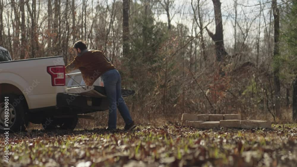 Man unloading bricks from a pickup truck and building an outdoor fire pit Man unloading bricks from a pickup truck and building an outdoor fire pit