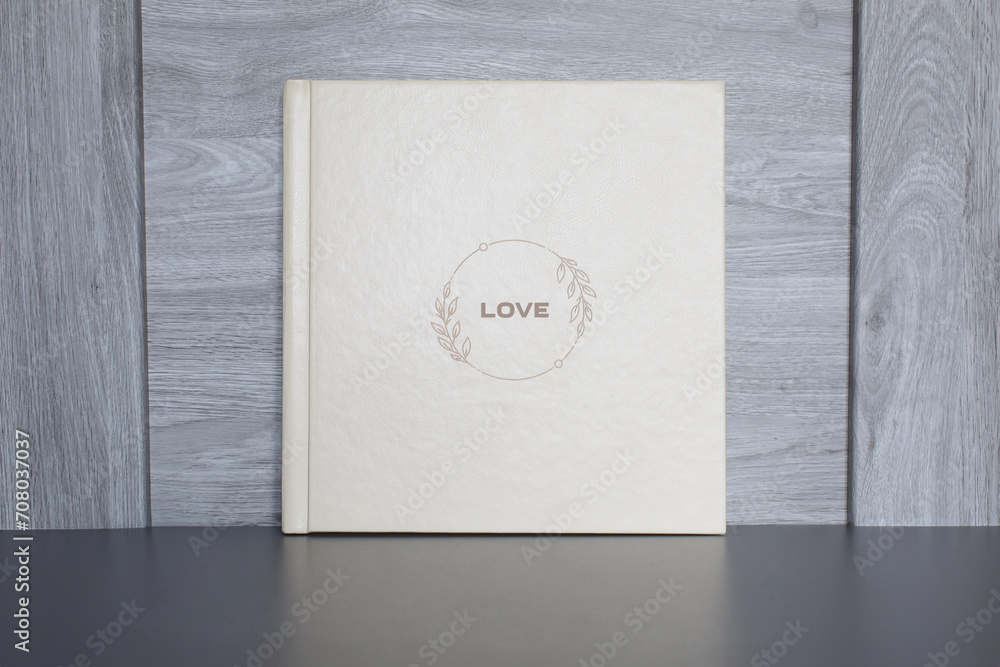 wedding or family photoalbum isolated on gray. Stylishphoto book. beige photo album with  cover  with a word love on gray background with copy space for text. pastel photo book close up portrait.  - obrazy, fototapety, plakaty 