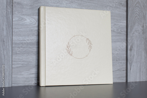 beige photo album with empty cover on wooden background with copy space for text. white photo book close up portrait. wedding or family photoalbum isolated on gray. Beautiful photo book. 