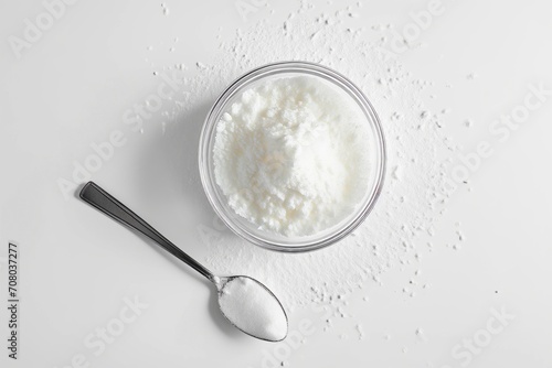 Top view of hydrolyzed collagen powder in a glass bowl with spoon on a white background photo