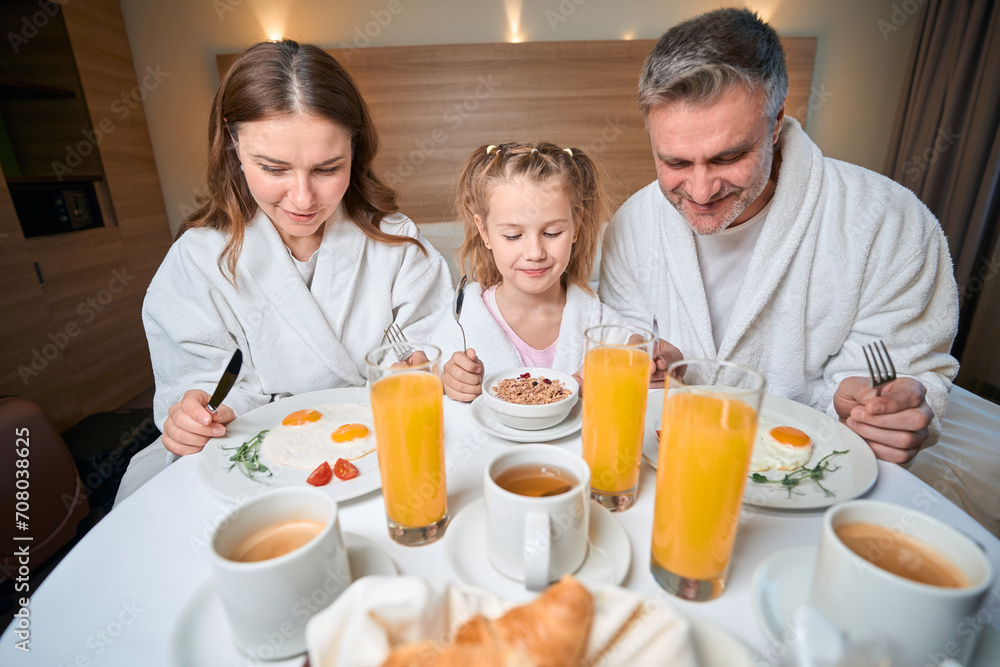 European family having breakfast on bed at table in hotel room European family having breakfast on bed at table in hotel room