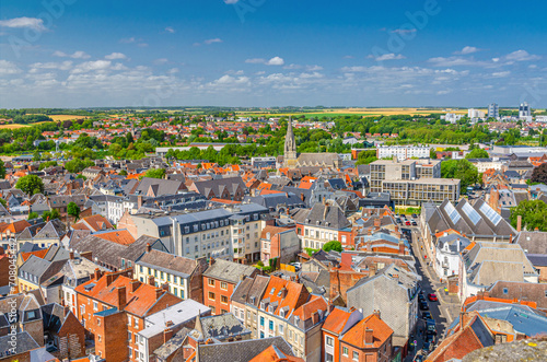 Aerial panoramic view of Arras city historical centre, historic quarter with old buildings and Eglise Saint-Gery Saint Gaugericus catholic church, green parks and fields, blue sky, Hauts-de-France