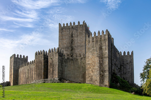 Guimaraes Castle in Guimaraes, Portugal, a hilltop Romanesque castle, founded in the 1000s and birthplace of Afonso Henriques against a clear blue sky photo