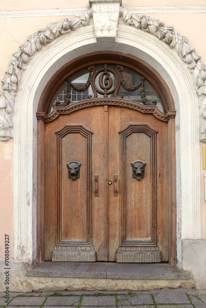 Ancient wooden arched door in Tallinn, excursion, Estonia, travel to Europe, sights, architecture, history, animal faces, monogram, coat of arms