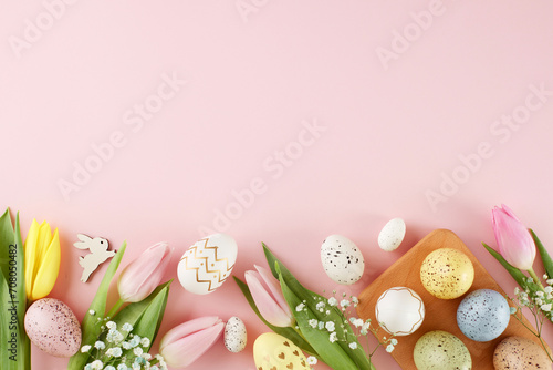Easter-themed decor concept. Top view photo of colorful eggs, fresh flowers, easter bunnies on pastel pink background with advert area