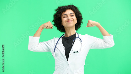 Female doctor, close-up, on a green background, shows strength