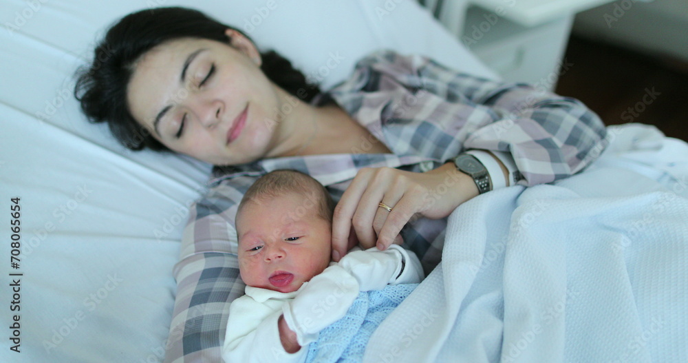 Mother holding newborn baby falling asleep together at hospital after birth in bed