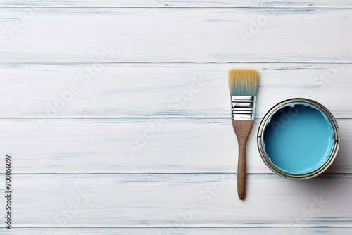 Metal paint can with blue paint and paintbrush on wooden table