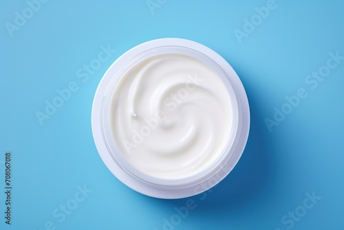 White plastic bowl of hand cream on blue background