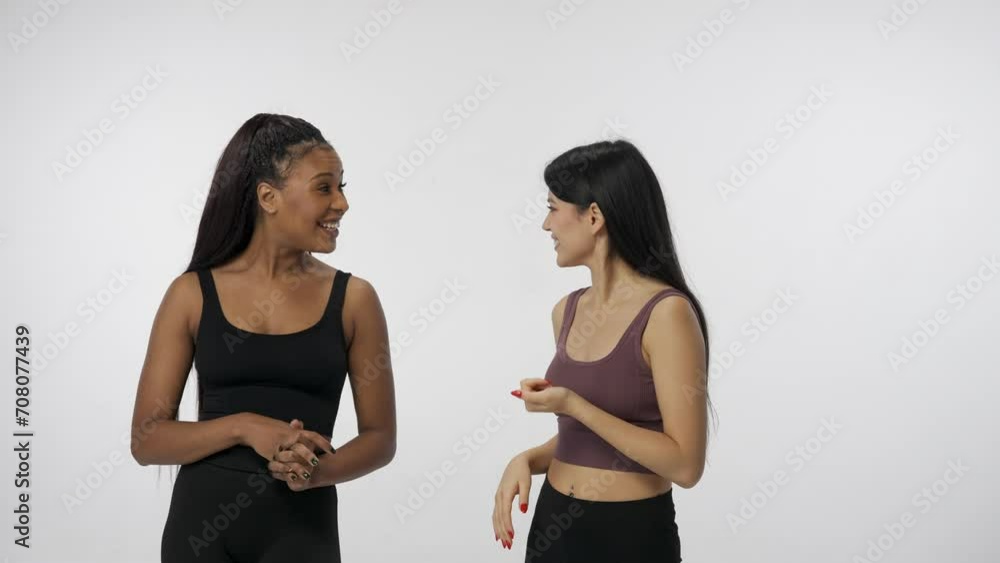 Portrait of young multiethnic models isolated on white studio background. Group of two positive multiracial girls smiling talking and hugging. Multiethnic beauty concept. Portrait of young multiethnic models isolated on white studio background. Group of two positive multiracial girls smiling talking and hugging. Multiethnic beauty concept.