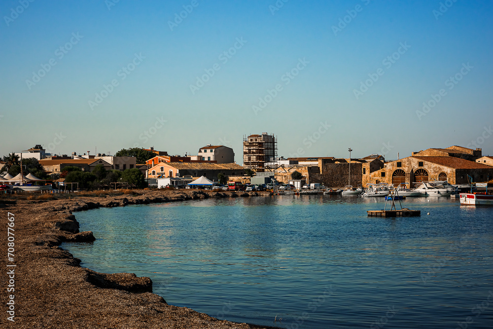the picturesque seaside village of Marzamemi. In the distance the buildings for storing boats