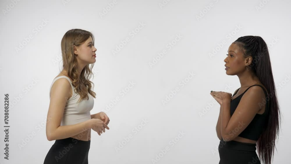Portrait of young multiracial models isolated on white studio background. Group of two beautiful multiethnic girls talk together and hug each other. Multiethnic beauty concept.