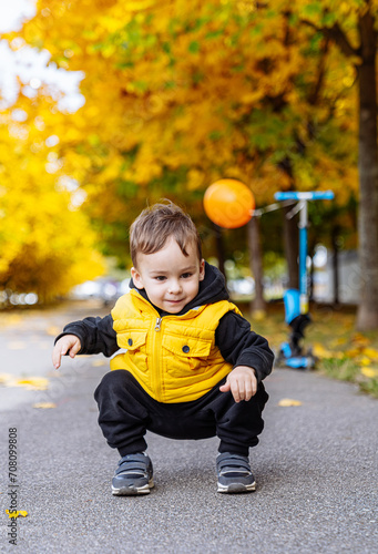 Young Boy in Yellow Jacket Playing With Ball. A cheerful young boy wearing a yellow jacket joyfully plays with his ball.