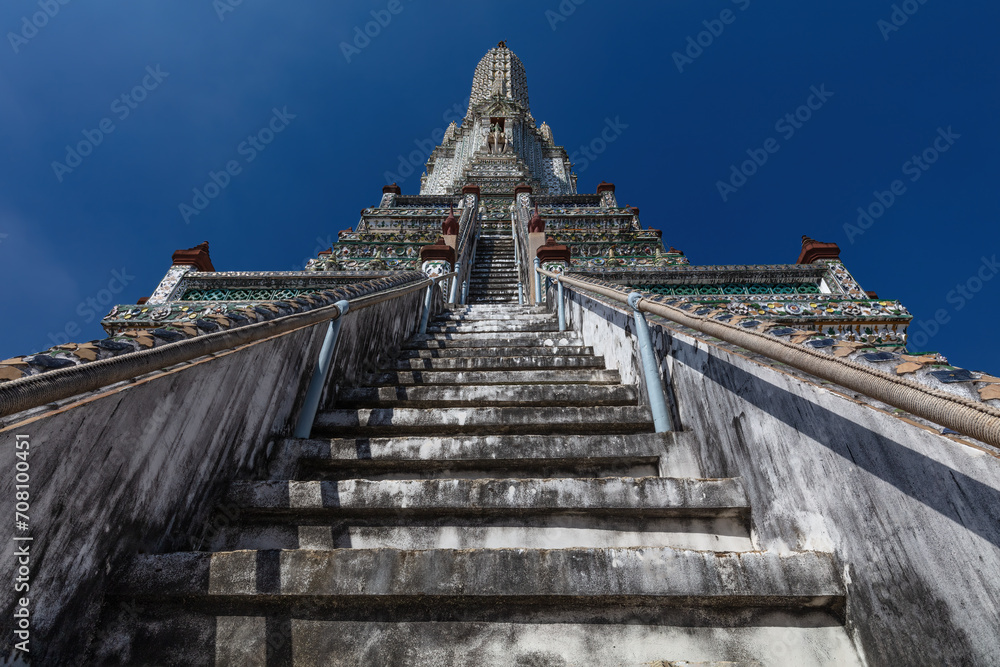 View of stairs on central prang of Wat Arun Temple (Temple of the Dawn), Bangkok, Thailand. Blue sky in background.

