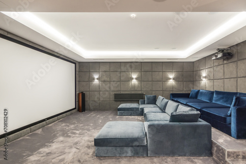 Home cinema in a private house with two wide sofas and a large screen.