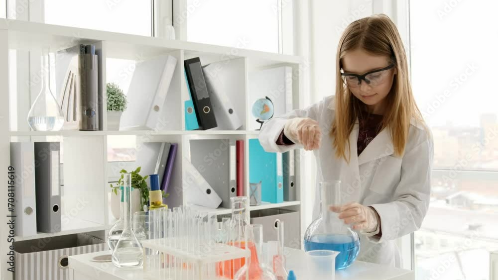 School girl wearing protection glasses works with liquids in chemistry class with concentration. Female pupil studying in lab with tubes and equipment School girl wearing protection glasses works with liquids in chemistry class with concentration. Female pupil studying in lab with tubes and equipment