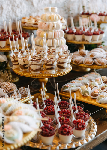 A dessert table at an event with a variety of sweets on golden stands. Candy bar at a wedding.