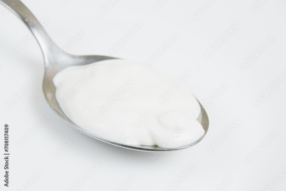 Sour cream or white sauce in a spoon on a white plate close-up Sour cream or white sauce in a spoon on a white plate close-up