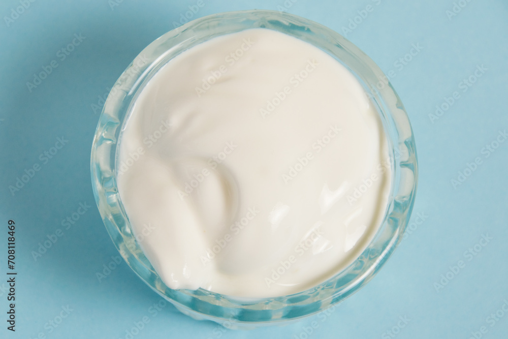 White sauce in a glass saucer on a blue background White sauce in a glass saucer on a blue background