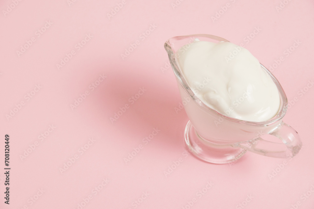 White sauce in a glass saucer on a pink background White sauce in a glass saucer on a pink background