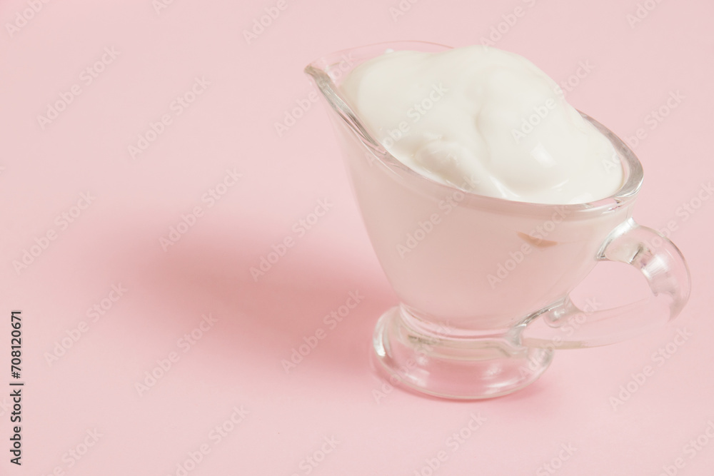 White sauce in a glass saucer on a pink background White sauce in a glass saucer on a pink background