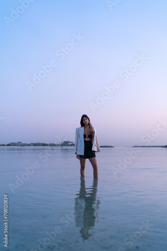 Portrait of a beautiful Middle eastern woman standing in the water wearing a jacket