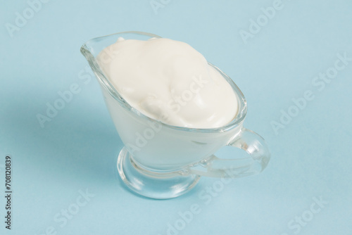 White sauce in a glass saucer on a blue background